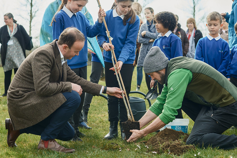 Cllr Richard Rout plants a new tree with school children from Howard Community Academy and Leisure/Forest school manager, Frank Carn-Pryor.