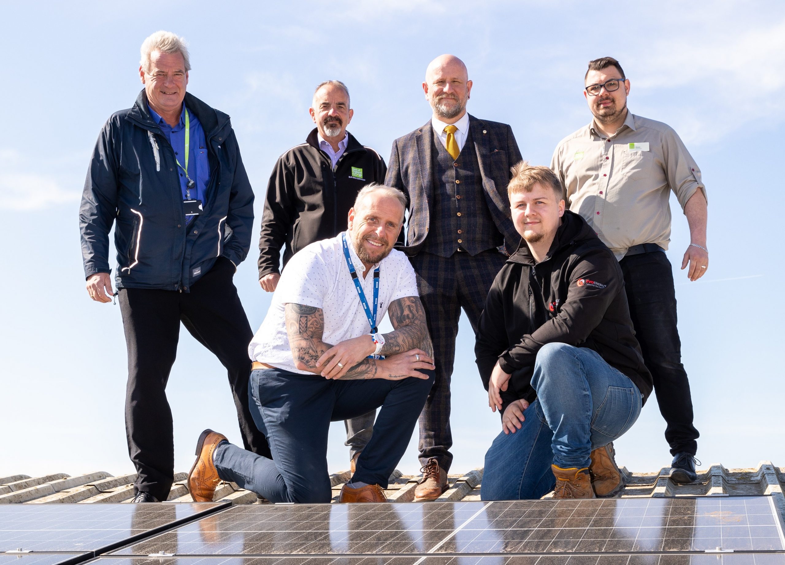 Six members of staff stood next to solar panels