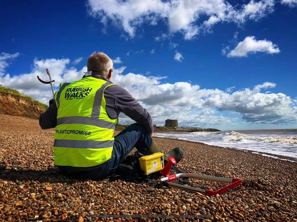 Jason Alexander of Rubbish Walks sits on a beach with his litter collecting equipment