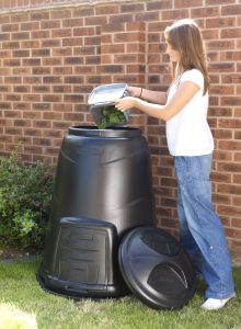 An image of a woman using a 330litre Black Compost Converter. 